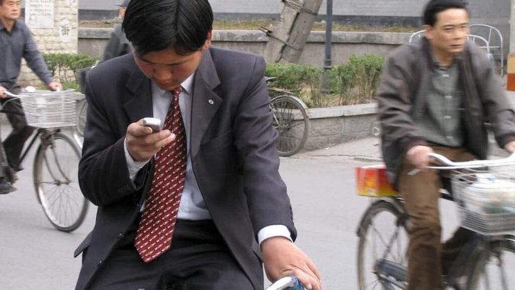 Ce cycliste s'est arrêté pour envoyer un message avec son smartphone. Ce sera la pratique à adopter désormais au Japon où il en coûtera cher de se servir de son engin tout en conduisant un deux-roues (Photo d'illustration).