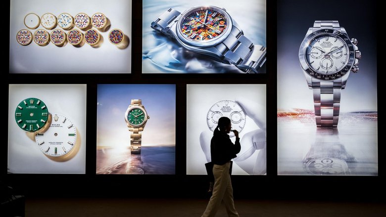 A visitor walks past photographs at the stand of Swiss luxury watchmaker Rolex during the opening day of the "Watches and Wonders Geneva" luxury watch fair, in Geneva, on April 14, 2026. The Geneva watch fair opened on April 14 and will be taken as a barometer of how the Middle East war is affecting the luxury goods sector. The Watches and Wonders salon -- the industry's biggest annual event -- sees 65 major watch brands, including Rolex, Patek Philippe, Cartier and Bulgari, display their latest creations until April 20. (Photo by Fabrice COFFRINI / AFP)
A visitor walks past photographs at the stand of Swiss luxury watchmaker Rolex during the opening day of the "Watches and Wonders Geneva" luxury watch fair, in Geneva, on April 14, 2026. The Geneva watch fair opened on April 14 and will be taken as a barometer of how the Middle East war is affecting the luxury goods sector. The Watches and Wonders salon -- the industry's biggest annual event -- sees 65 major watch brands, including Rolex, Patek Philippe, Cartier and Bulgari, display their latest creations until April 20. (Photo by Fabrice COFFRINI / AFP) A visitor walks past photographs at the stand of Swiss luxury watchmaker Rolex during the opening day of the "Watches and Wonders Geneva" luxury watch fair, in Geneva, on April 14, 2026. The Geneva watch fair opened on April 14 and will be taken as a barometer of how the Middle East war is affecting the luxury goods sector. The Watches and Wonders salon -- the industry's biggest annual event -- sees 65 major watch brands, including Rolex, Patek Philippe, Cartier and Bulgari, display their latest creations until April 20. (Photo by Fabrice COFFRINI / AFP)