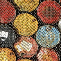 Barils de pétrole derrière une clôture grillagée.