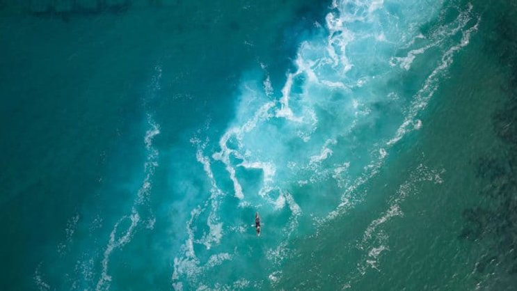 Top view  of a man paddles a kayak in raging sea water