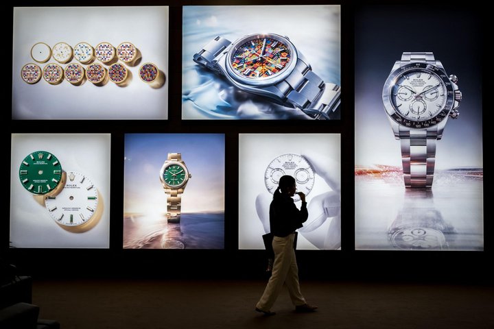 A visitor walks past photographs at the stand of Swiss luxury watchmaker Rolex during the opening day of the "Watches and Wonders Geneva" luxury watch fair, in Geneva, on April 14, 2026. The Geneva watch fair opened on April 14 and will be taken as a barometer of how the Middle East war is affecting the luxury goods sector. The Watches and Wonders salon -- the industry's biggest annual event -- sees 65 major watch brands, including Rolex, Patek Philippe, Cartier and Bulgari, display their latest creations until April 20. (Photo by Fabrice COFFRINI / AFP)
A visitor walks past photographs at the stand of Swiss luxury watchmaker Rolex during the opening day of the "Watches and Wonders Geneva" luxury watch fair, in Geneva, on April 14, 2026. The Geneva watch fair opened on April 14 and will be taken as a barometer of how the Middle East war is affecting the luxury goods sector. The Watches and Wonders salon -- the industry's biggest annual event -- sees 65 major watch brands, including Rolex, Patek Philippe, Cartier and Bulgari, display their latest creations until April 20. (Photo by Fabrice COFFRINI / AFP)