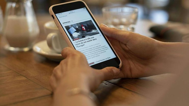 Une personne consulte le journal Le Temps sur son smartphone: de nombreux titres sont utilisés de manière croissante en ligne plutôt que sur papier.