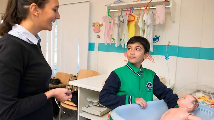 Une étudiante de 2e année donne des conseils à un jeune garçon pour nettoyer un nouveau-né dans l'atelier sage-femme de la Haute Ecole de santé Vaud à Lausanne.