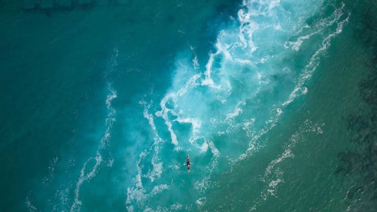 Top view  of a man paddles a kayak in raging sea water